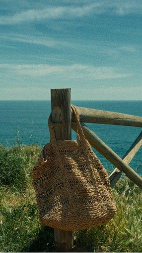 a bag hanging on a wooden fence by the ocean